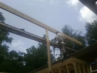 Carpenter setting a ridge beam over a new addition frame — Ice Dam Removal by Roofing Brothers in China Grove