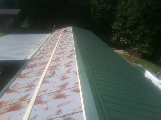 Old rusted panels beside newly installed green metal roofing — Wind Damage Roof Repair by Roofing Brothers in China Grove